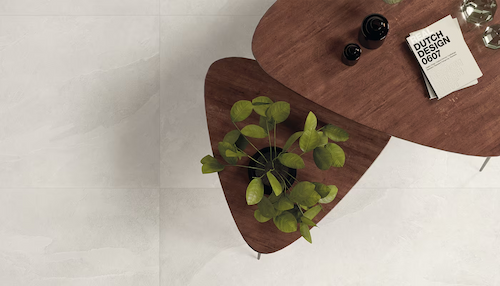 Ergon Cornerstone – jasne płytki gresowe imitujące kamień na podłodze w nowoczesnym wnętrzu z drewnianym stolikiem